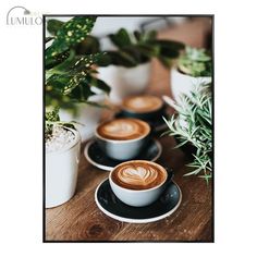 two cups of coffee sit on a table next to potted plants