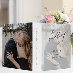 a wedding album with an image of a couple kissing on the cover and flowers in the background