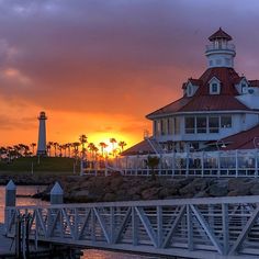 the sun is setting behind a large white building with a light house on it's roof