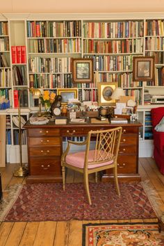 a room with many bookshelves and a desk in the middle, along with a couch