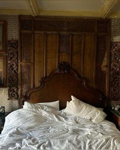 a bed with white sheets and pillows in a room that has wood paneling on the walls