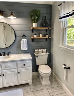 a white toilet sitting next to a sink in a bathroom under a mirror and lights