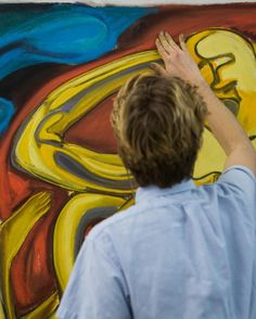 a boy is painting on the wall with his hands and arm in front of him