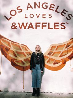 a woman standing in front of a sign that says los angeles loves & waffles