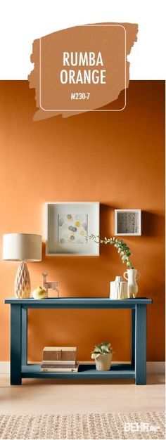 a living room with an orange wall and blue table in the center, along with two lamps on either side