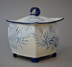 a blue and white pot with a handle on it's side, sitting on a table