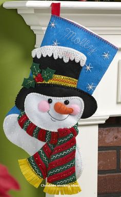 a snowman ornament hanging from a mantel with a christmas stocking on it