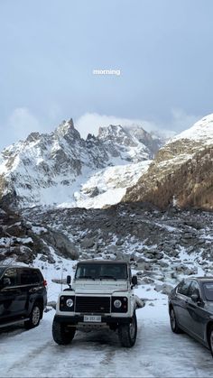 three vehicles parked in the snow near mountains