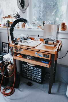 a work station in the corner of a room next to a window with lots of clutter on it