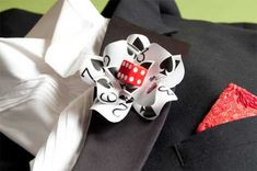 a red dice sitting on top of a black cloth next to a white tie and pocket square