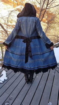 a woman in a jean jacket and boots is walking on a wooden deck with snow