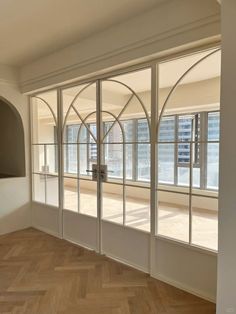 an empty room with large windows and wooden floors