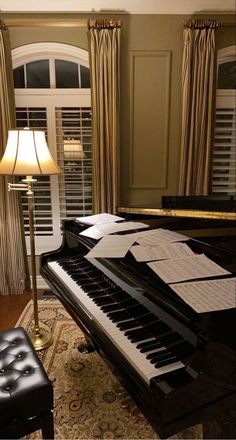 a grand piano with sheet music on it next to a lamp in a living room