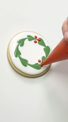 a cookie decorated like a christmas wreath being held by a hand