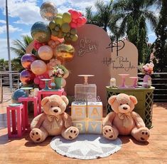 two teddy bears sitting on the ground in front of a birthday party sign and balloons