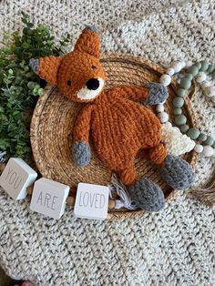 a knitted teddy bear laying on top of a woven basket next to some beads