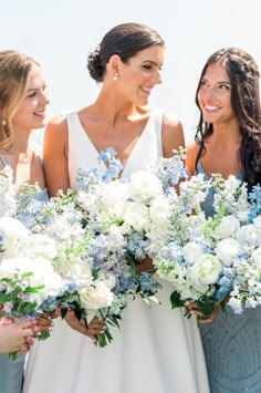 three bridesmaids holding bouquets of white and blue flowers