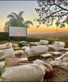 an outdoor movie is set up in the grass with white pillows and chairs around it