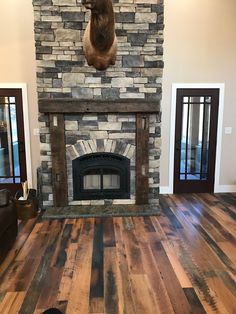 a dog laying on the floor in front of a stone fireplace with a deer head mounted above it