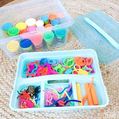 two plastic containers filled with craft supplies on top of a table