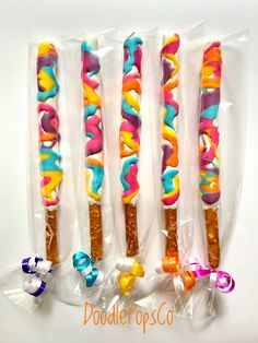 four candy sticks with different colors and designs in plastic wrappers on a white background