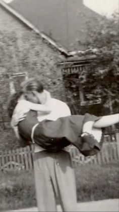 an old black and white photo of a man holding a woman