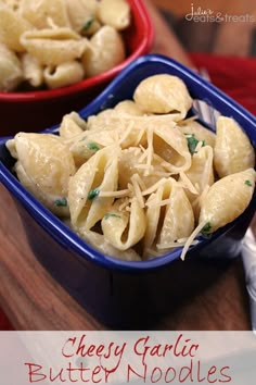 two bowls filled with pasta and cheese on top of a wooden table next to silverware