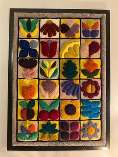 an art work made out of felt with flowers and leaves on the bottom, surrounded by smaller squares