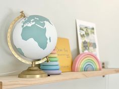 a small globe sitting on top of a wooden shelf next to other toys and books