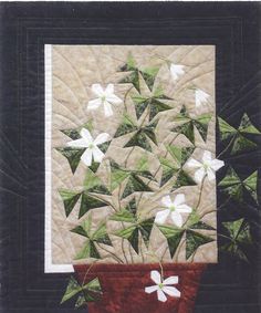 a potted plant with white flowers in it on a black and white quilted background