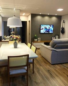 a dining room table with chairs and a couch in front of a flat screen tv