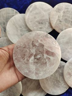 a person holding a crystal stone in front of some other stones on a blue and white background