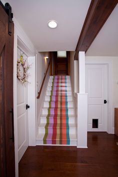 the stairs are painted with multicolored stripes and wood trimmings in this hallway