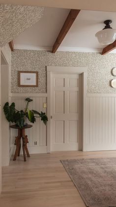 a living room with wood floors and white walls, two planters on either side of the door