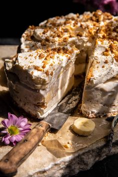 a piece of cake on a cutting board with a knife and flower next to it