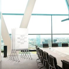 a conference room with chairs and a white board on the table in front of large windows