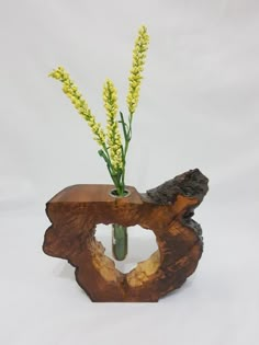 a vase with flowers in it sitting on top of a piece of driftwood that has been carved into the shape of a tree stump