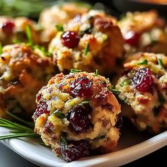 a white plate topped with crab cakes covered in cranberry sauce and garnished with green leaves