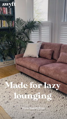 a brown couch sitting on top of a rug next to a window