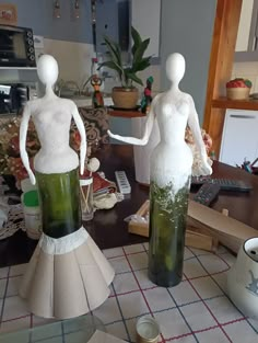 two mannequins made out of wine bottles sitting on top of a table