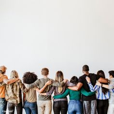 a group of people standing next to each other in front of a white wall with their arms around each other