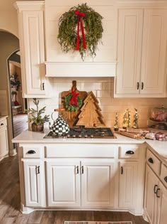 a kitchen decorated for christmas with wreaths on the stove top and wooden house decorations