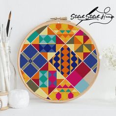 a colorful cross stitch pattern on a wooden hoop