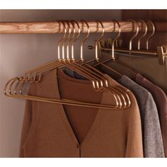 a wooden coat rack with clothes hanging from it's hooks and two coats on hangers