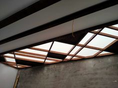 an unfinished room with wooden beams and skylights on the ceiling, in front of a concrete wall