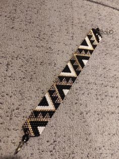 a black and white beaded bracelet laying on top of a gray carpeted floor