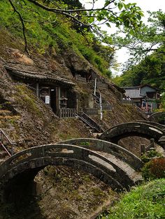 there are many small bridges on the side of this hill that leads to an old house