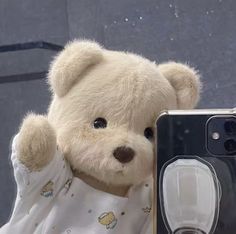 a teddy bear is posed next to an old camera and its case for the iphone