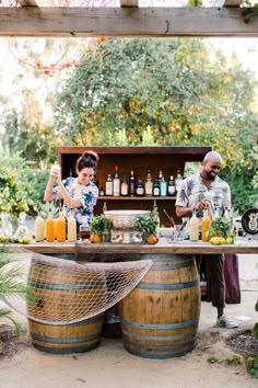 two people standing at a bar with bottles on it