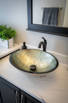 a bathroom sink sitting under a mirror next to a counter top with a potted plant